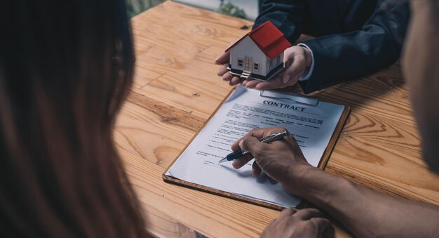 Discussion with a real estate agent House model with agent and customer discussing for the contract to buy get insurance or loan real estate or property