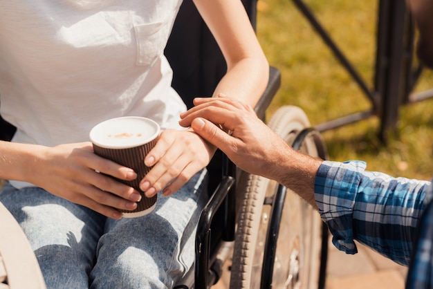 Disease woman is holding a glass with coffee in hands.