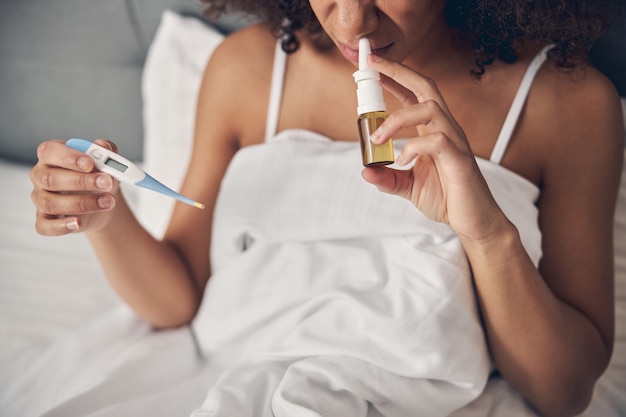 diseased female holding a bottle of nasal spray in her hand