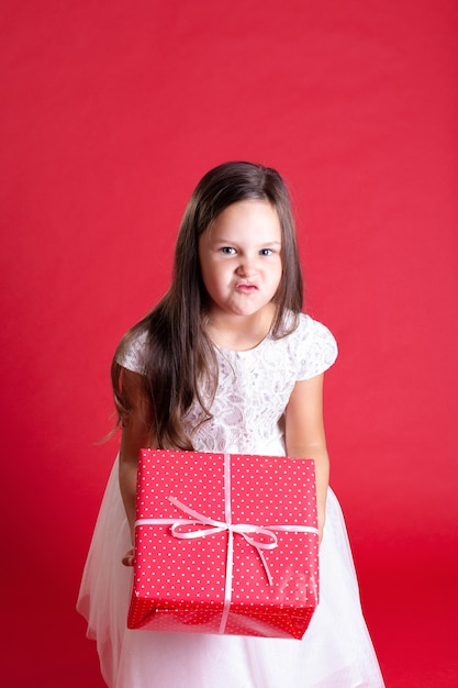 Disgruntled girl  in white dress holding a gift