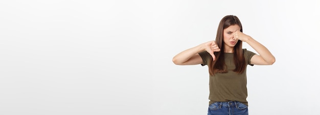 Disgusted young blonde closing her nose with her fingers isolated over white background