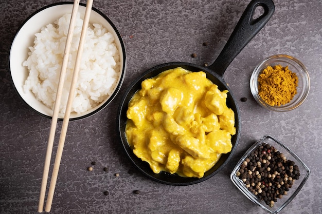 A dish of Asian cuisine Chicken cooked in curry sauce rice and spices on a gray background