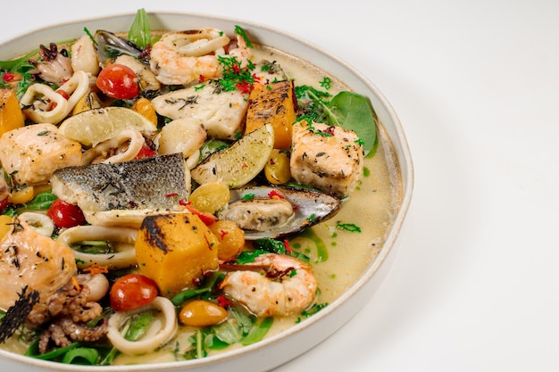 Dish of boiled dorada fish with shellfish vegetables and herbs