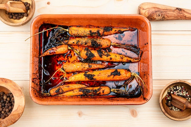 A dish of carrots with a bottle of wine on the side.