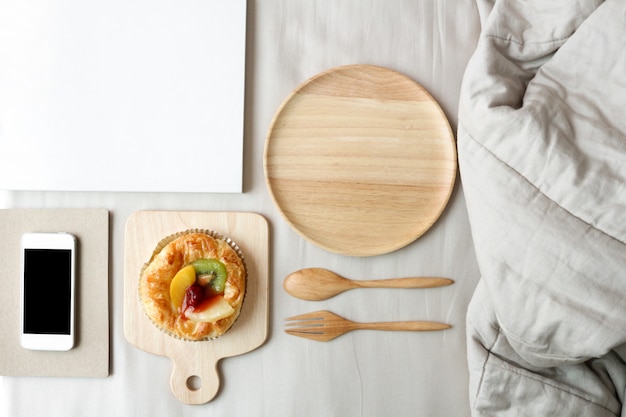 Dish of mixed fruits pies is on top of the bed. Breakfast in bed concept. 