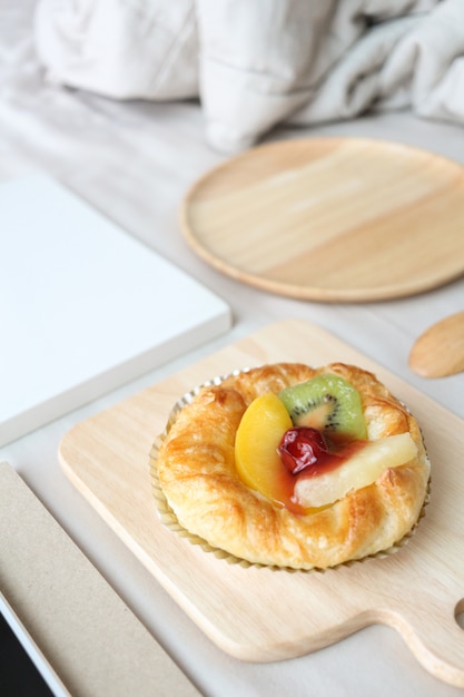 Dish of mixed fruits pies is on top of the bed. Breakfast in bed concept.