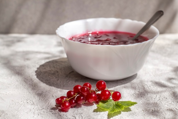 A dish with delicious freshly boiled red currant jam on a light table