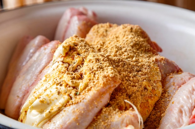 Dish with fresh raw wings sprinkled with spices on a wooden table