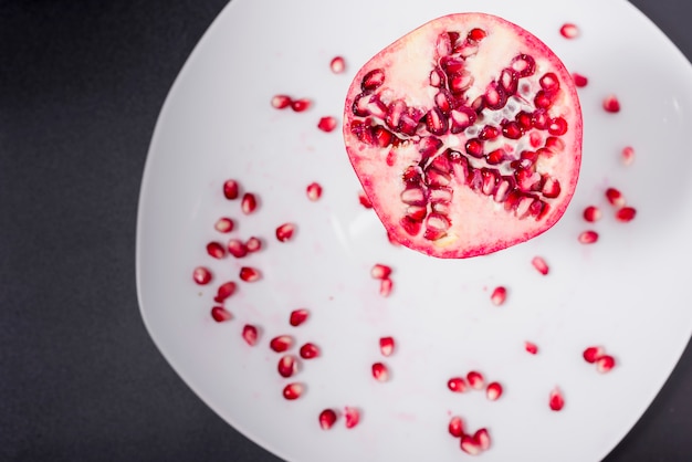 Dish with pomegranate seeds out of focus and half pomegranate