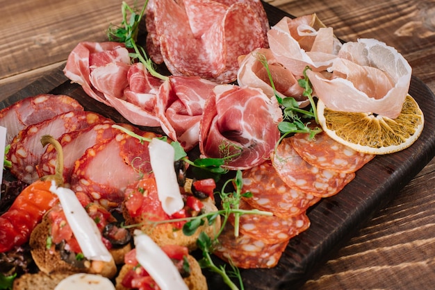 A dish with variety of smoked meat, salamy, ham on wooden background