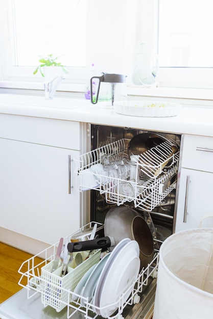 Dishwasher filled with dirty dishes with open door in home kitchen