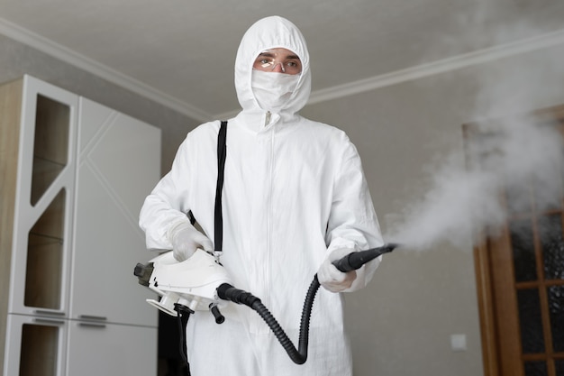 Disinfector in a protective suit conducts disinfection in home. professional disinfection against COVID-19, coronavirus. in clothing protecting from chemical poisoning in the industry