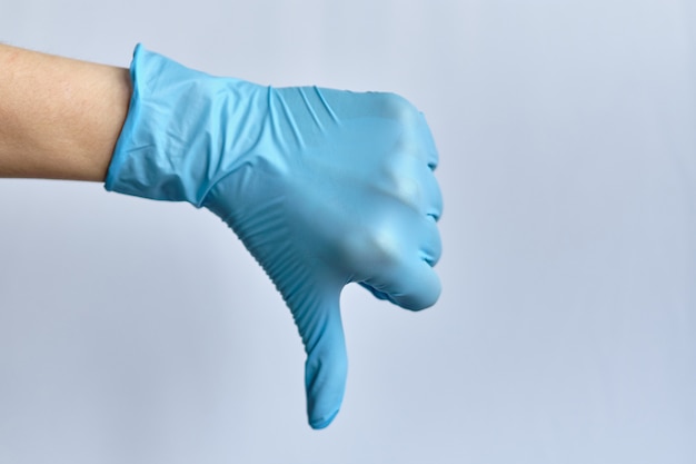 Dislike concept - hand in a medical glove on a white background. Copy space.