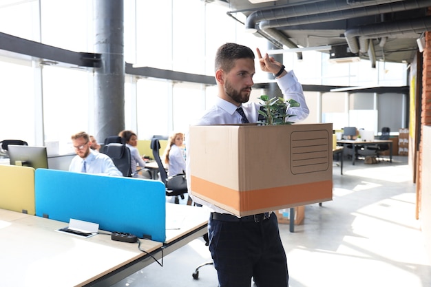 Dismissed worker going from the office with his office supplies showing fuck.