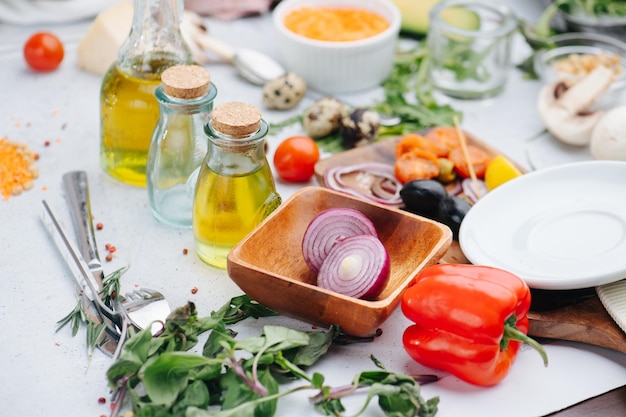 Disorderly table full with ingredients for salad Olives onions oil and greens