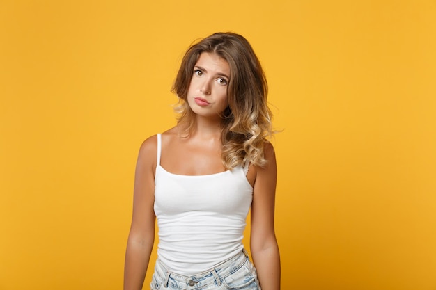 Displeased offended young woman girl in light casual clothes posing isolated on yellow orange background studio portrait. People sincere emotions lifestyle concept. Mock up copy space. Looking camera.