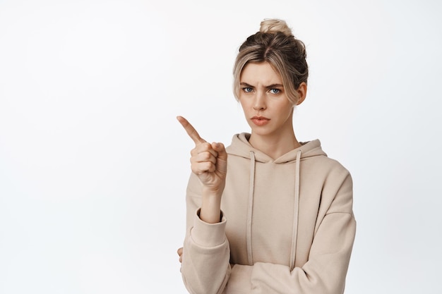 Displeased strict girl shaking finger warn you prohibit something bad scolding someone standing over white background