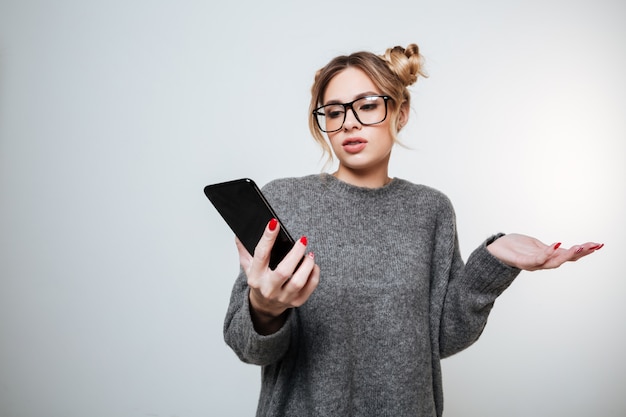 Displeased woman in sweater and eyeglasses with phone