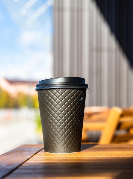 Disposable eco paper cup for drink with background of the city Takeaway drink Empty space for text