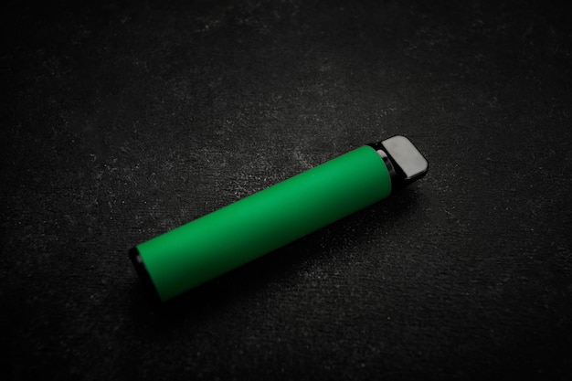 Disposable electronic cigarette of green color on gray background