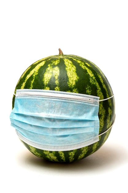 Disposable protective mask on a green ripe watermelon