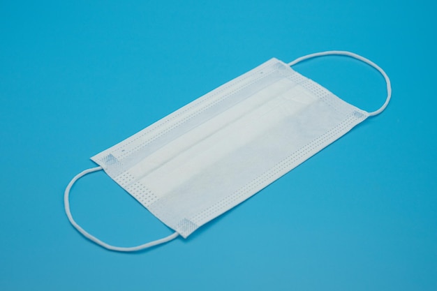 Disposable protective masks of various colors on a blue background