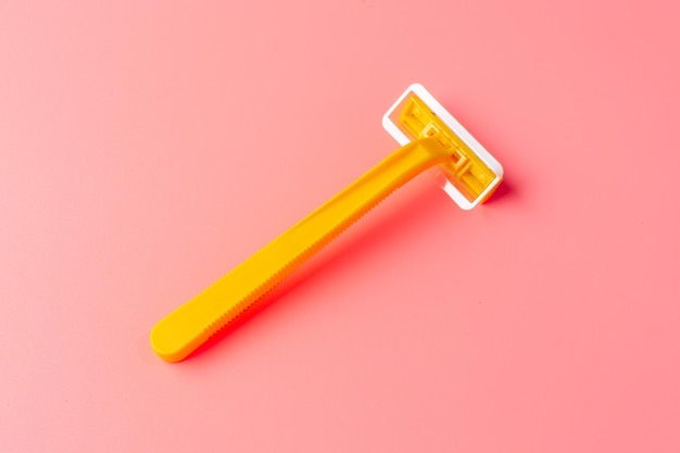 Disposable shaver on a light pink background