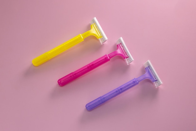 Disposable shaving razor for hair removal on pink background