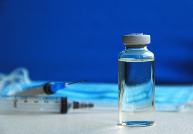 disposable syringe with vaccine and blue medical masks