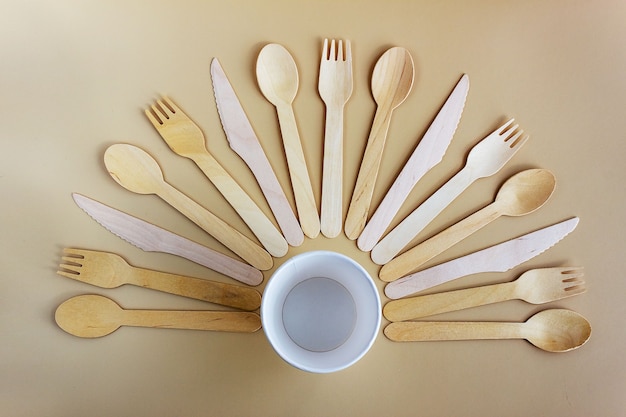 Disposable tableware made from natural materials, wooden spoon, fork, knife, paper cup. Biodegradable picnic tableware, modern replacement for plastic.