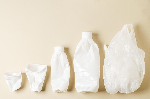 Disposable white plastic tableware on a beige background The concept of nature pollution Copy space