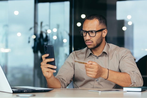 Dissatisfied and angry african american businessman inside office trying to make a bank transfer man