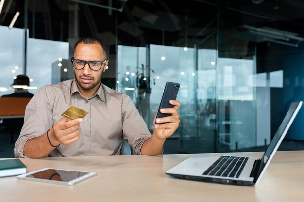 Dissatisfied and angry businessman in office trying to make purchase in online store hispanic man