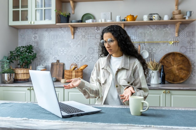 Dissatisfied and disappointed woman at home looking at laptop latin american woman got error