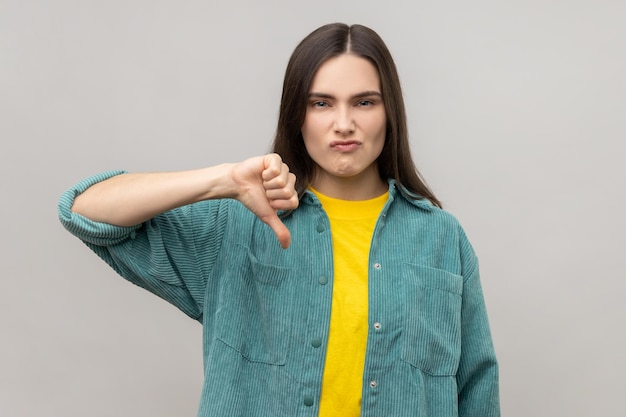 Dissatisfied woman showing thumb down disapproval sign gesturing dislike to bad service