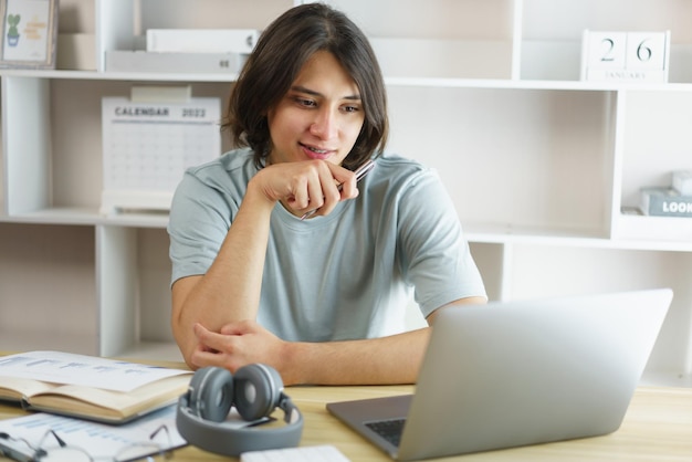 Distance education concept Teen boy sitting to contemplate while listening lecture online at home