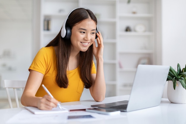 Distance learning asian woman in headset study online with laptop at home