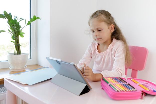 Distance learning online education girl studying at home with digital tablet laptop notebook and doing homework