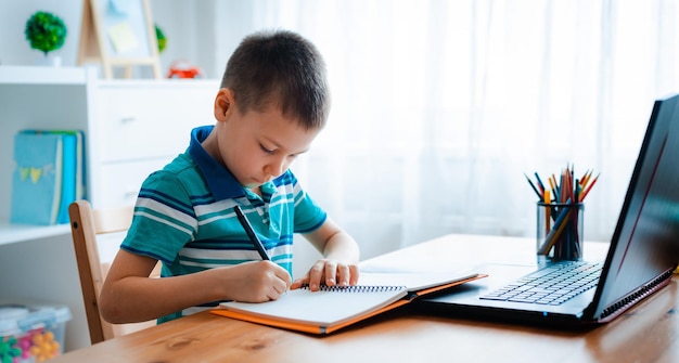 Distance learning online education A schoolboy boy studies at home and does school homework A home distance learning