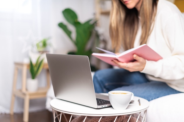 Distance learning online education and work. Business woman with coffee mug writes in notebook.