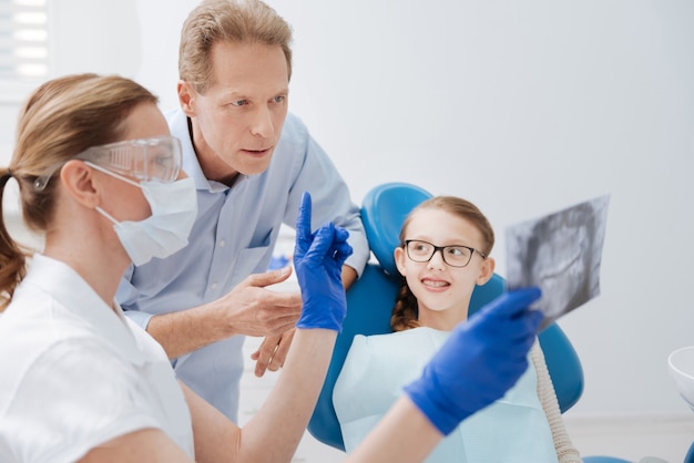 Photo distinguished trained young doctor looking at the scan and making her conclusions while the family waiting for results