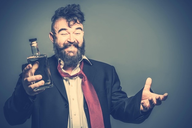 Distorted image of a bearded man in suit and a red tie with a bottle of alcohol in his hand Toned