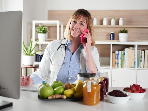 Distracted female nutritionist chatting with smartphone in office studio