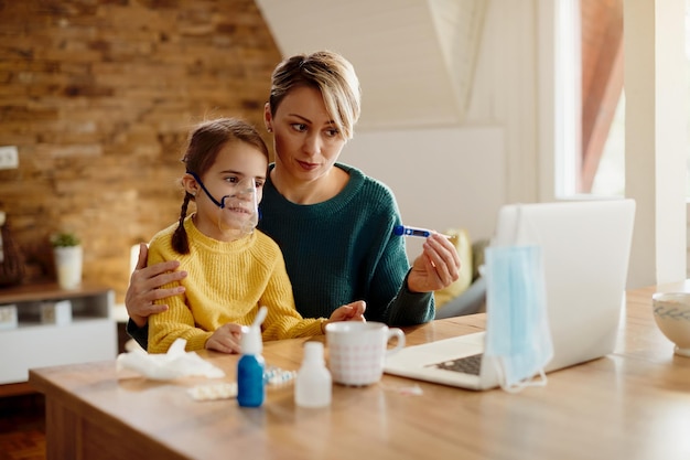 Distraught mother and her small daughter having video call with a doctor from home