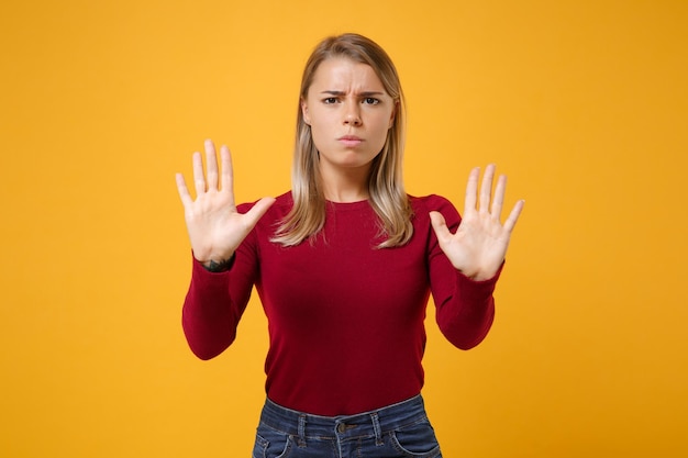 Disturbed young blonde woman girl in casual clothes posing isolated on yellow orange background studio portrait. People emotions lifestyle concept. Mock up copy space. Rising hands up, showing palms.