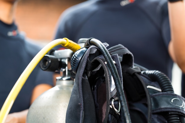 divemaster and students at the diver Course on holiday wearing a wetsuit or diving in the foreground is a oxygen tank