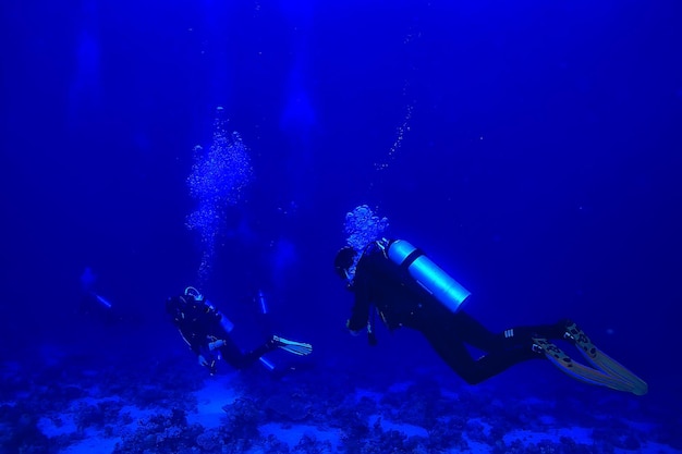 divers underwater at depth in the blue sea background