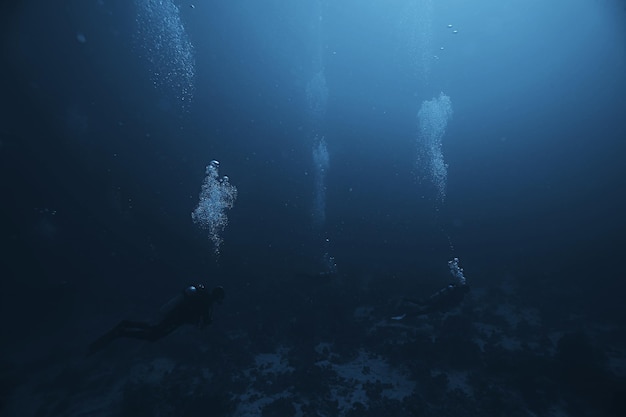 divers underwater at depth in the blue sea background