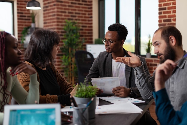 Diverse businesspeople discussing marketing turnover planning business collaboration during corporate meeting in startup office. Multi-ethnic team brainstorming ideas working at management strategy