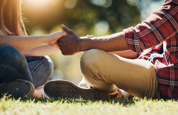 Diverse couple and holding hands in a park for love care and affection in a summer garden or park Interracial man and woman bonding while hold hand for vacation getwaway in a natural environment